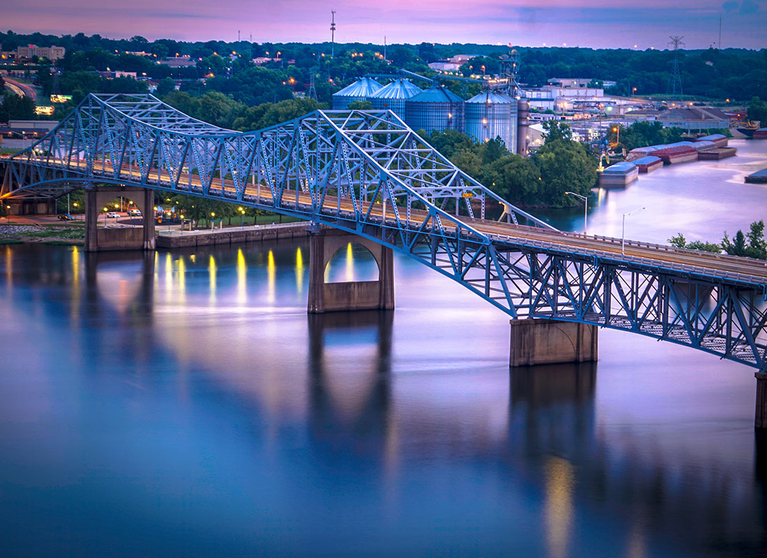Florence, AL - Scenic View of a Bridge in the Evening Across a River in Downtown Florence Alabama with Commercial and Industrial Buildings in the Background