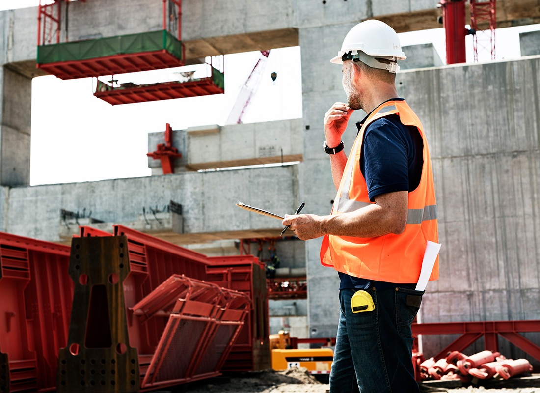 Insurance by Industry - View of a Contractor Holding a Tablet at a Construction Jobsite Inspecting the New Building Progress