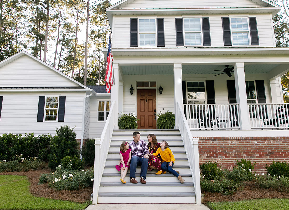 Personal Insurance - View of a Family with Two Children Sitting on the Front Steps of Their New Two Story Home with a Well Manicured Front Yard